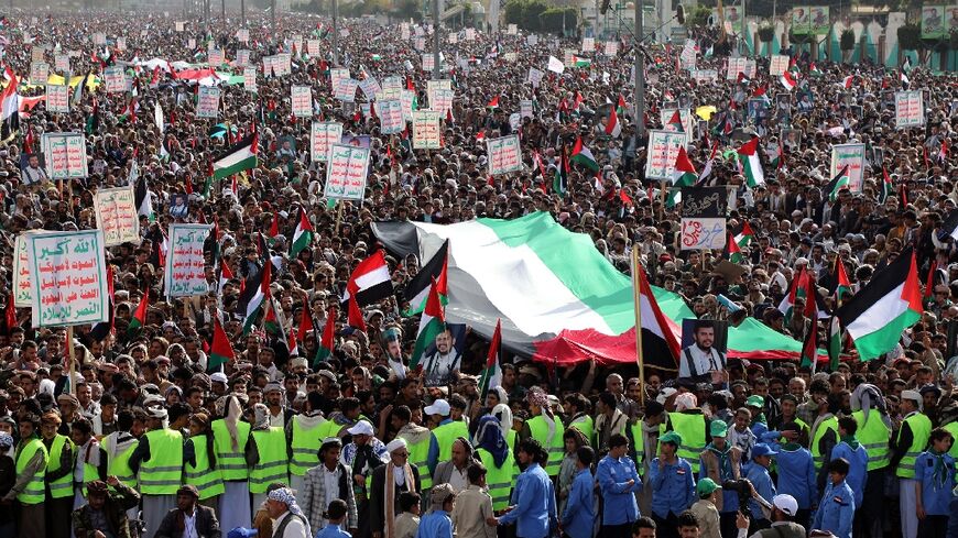 Demonstrators hold placards and wave a giant Palestinian flag during a march in solidarity with the people of Gaza in the Huthi-controlled capital Sanaa on January 5, 2024 