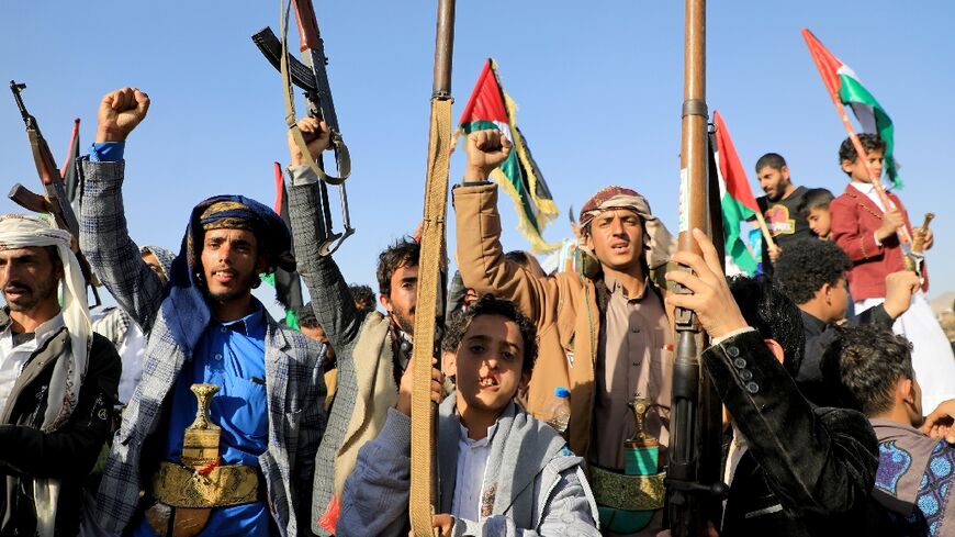 Huthi fighters brandish weapons during a protest in Sanaa on January 12, 2024 following US and British forces strikes targeting the Yemeni rebel group