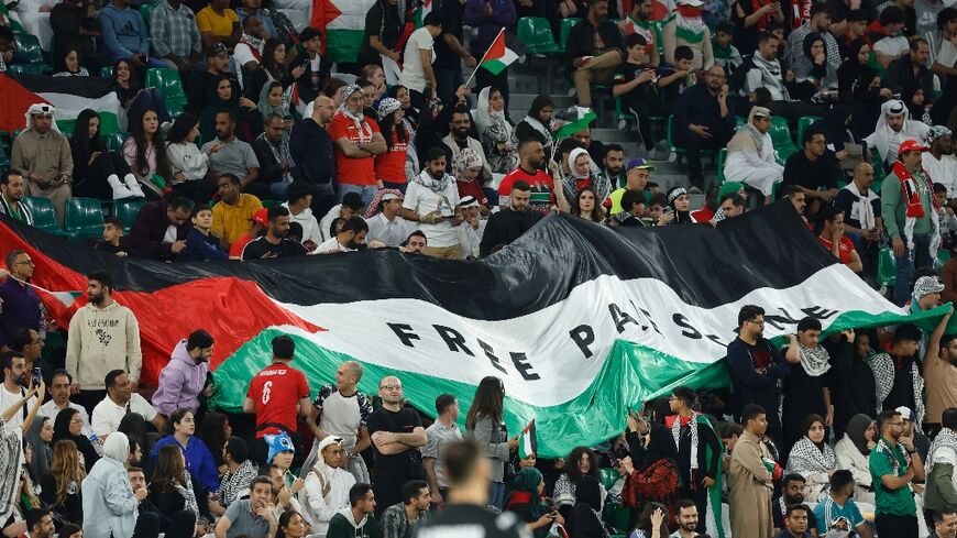 Football fans unfurl a giant Palestinian flag emblazoned with the slogan 'Free Palestine'in the stands during the Qatar 2023 AFC Asian Cup Group C football match between Iran and Palestine