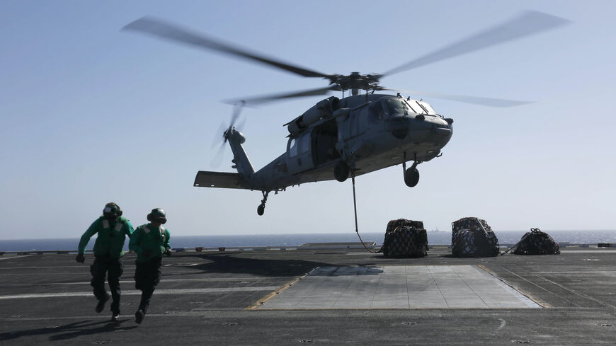 In this handout photo provided by the U.S. Navy, Logistics Specialist 1st Class Ousseinou Kaba (left), from Silver Spring, Md., and Logistics Specialist Seaman Abigail Marshke, from Flint, Mich., attach cargo to an MH-60S Sea Hawk helicopter from the "Nightdippers" of Helicopter Sea Combat Squadron (HSC) 5 from the flight deck of the Nimitz-class aircraft carrier USS Abraham Lincoln (CVN 72) May 10, 2019 in the Red Sea. 
