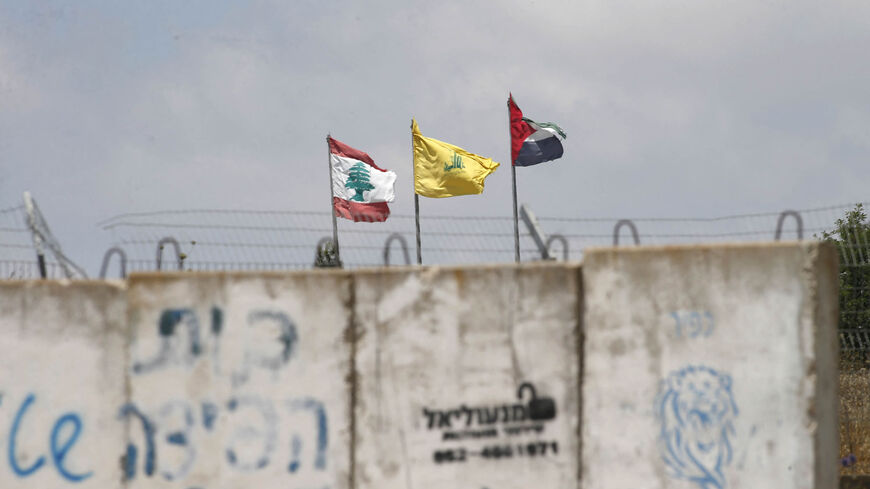 A picture taken on July 3, 2022 from the Israeli Kibutz of Baram, shows the flags of (L to R) Lebanon, Hezbollah and Palestine swaying in the wind on the Lebanese side of the border with Israel. 