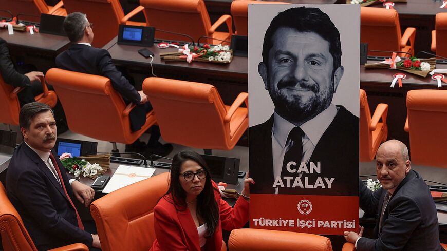 Erkan Bas (L), leader of the Workers' Party of Turkey (TIP), and fellow party MPs Sera Kadigil (C) and Ahmet Sik (R) display a portrait of jailed TIP MP Can Atalay, during a swearing-in ceremony at the Turkish parliament in Ankara, June 2, 2023.