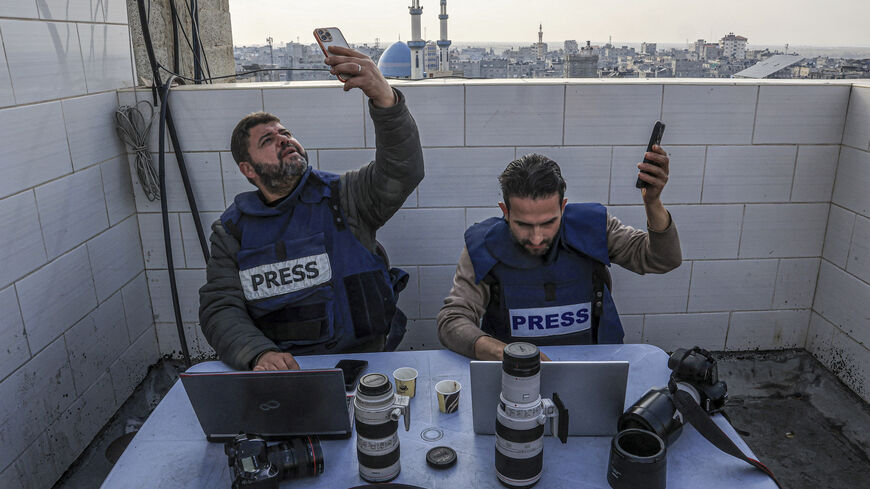 TOPSHOT - Palestinian journalists attempt to connect to the internet using their phones in Rafah on the southern Gaza Strip on December 27, 2023, amid continuing battles between Israel and the Palestinian militant group Hamas. Power cuts have become a fact of life in war-torn Gaza. But thanks to embedded SIM cards, Palestinians can still access the internet and stay in touch with loved ones abroad. (Photo by SAID KHATIB / AFP) (Photo by SAID KHATIB/AFP via Getty Images)