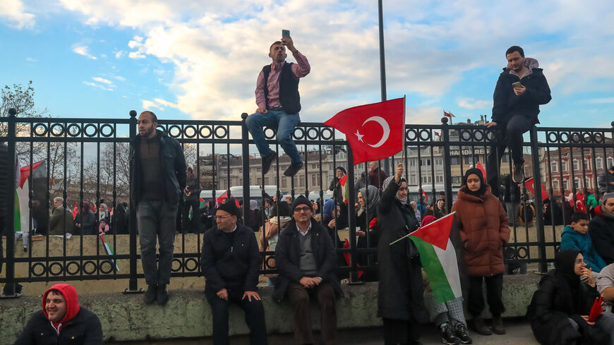 01/01/2024, Istanbul, Turkey. People sits on the iron fences to watch and participate the solidarity march. Thousands gathered in Istanbul Galata Bridge in a demonstration expressing solidarity with the Palestinian people amid the ongoing conflict between Israel and Palestine. (Photo by Ilker Eray / Middle East Images / Middle East Images via AFP) (Photo by ILKER ERAY/Middle East Images/AFP via Getty Images)