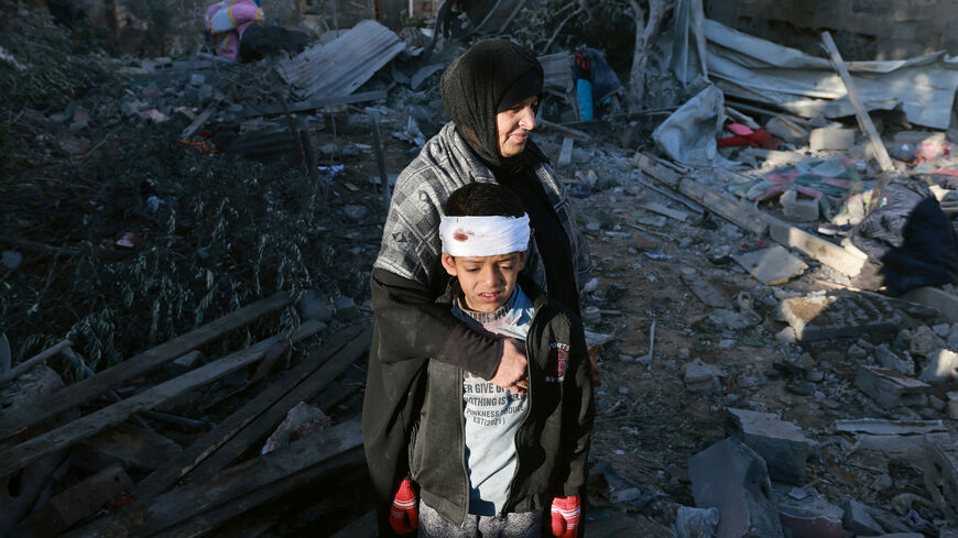 A Palestinian woman embraces a lightly injured boy as they check the rubble of a building following Israeli bombardment, on January 18, 2024 in Rafah in the southern Gaza Strip, amid ongoing battles between Israel and the Palestinian militant group Hamas.
