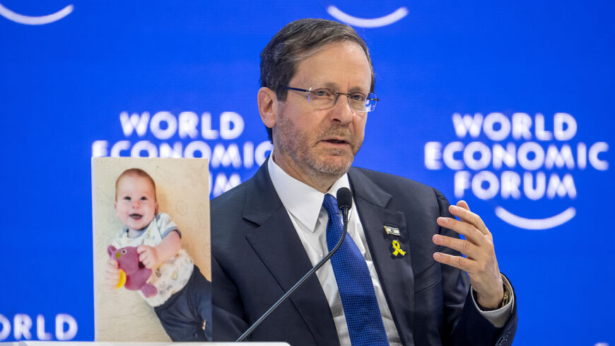 Israeli President Isaac Herzog speaks next to a photograph showing 10-month-old baby Kfir Bibas held by Hamas during a session of the World Economic Forum (WEF) meeting in Davos on January 18, 2024. (Photo by Fabrice COFFRINI / AFP) (Photo by FABRICE COFFRINI/AFP via Getty Images)