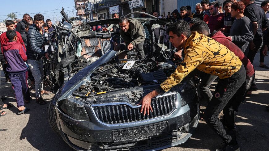 Crowds examine the car in which two journalists, Mustafa Thuria, a video stringer for AFP news agency, and Hamza Wael Dahdouh, a journalist with Al Jazeera television network, were killed in an air strike on Rafah blamed by Hamas on Israel
