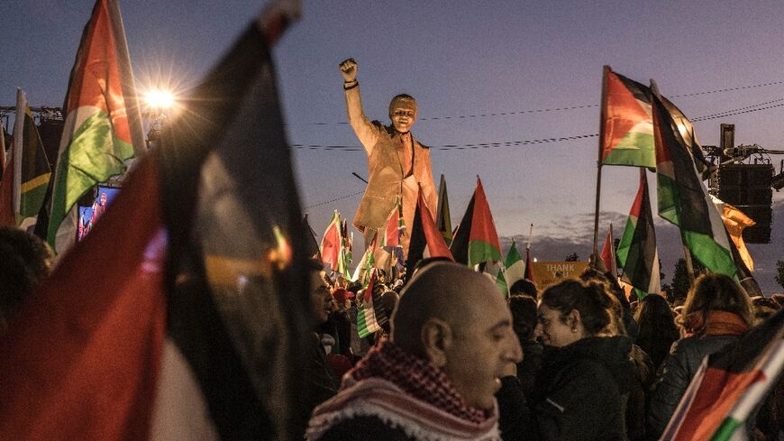 Palestinians gather around a statue of late South African president Nelson Mandela in Ramallah to celebrate a landmark "genocide" case filed by South Africa against Israel at the International Court of Justice