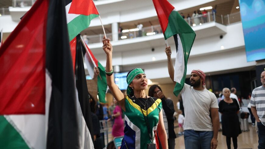 South Africans wave Palestinian flags as they wait to greet members of the country's legal team bringing a case against Israel at The Hague