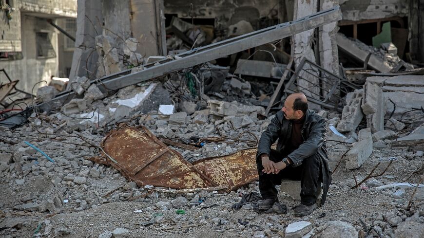 A Palestinian man sits amid the rubble of a building destroyed during Israeli strikes in Gaza City