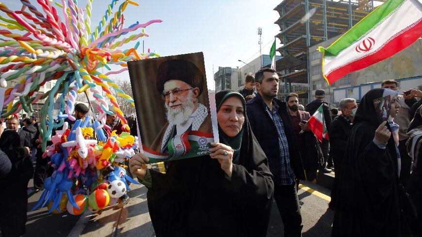 A woman raises a portrait of Iran's Supreme Leader Ayatollah Ali Khamenei, as people gather to mark the 45th anniversary of the Islamic revolution in Tehran on February 11, 2024