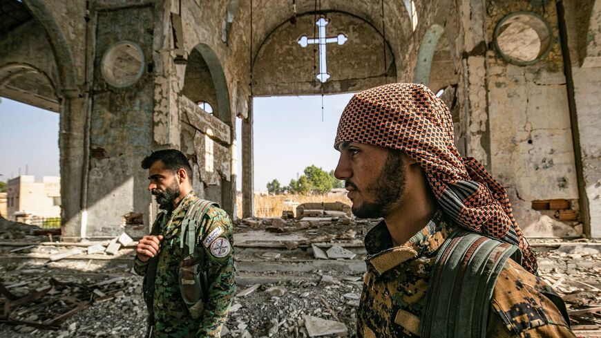 Members of the Khabour Guards (MNK) Assyrian Syrian militia, affiliated with the Syrian Democratic Forces (SDF), walk in the ruins of the Assyrian Church of the Virgin Mary, which was previously destroyed by Islamic State (IS) group fighters, in the village of Tal Nasri south of the town of Tal Tamr in Syria's northeastern Hasakah province on Nov. 15, 2019.