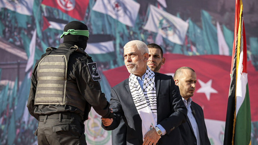 Yahia al-Sinwar (C), Gaza Strip chief of the Palestinian Islamist Hamas movement, shakes hands with a masked fighter of Hamas' Qassam Brigades during a rally marking the 35th anniversary of the group's foundation, in Gaza City on December 14, 2022. - Hamas will end talks on securing a prisoner exchange with Israel unless there is progress soon, the militant group's leader in the Gaza Strip said on December 14. Since Israel's 2014 invasion of the Gaza Strip, the Islamist group has held the bodies of Israeli 