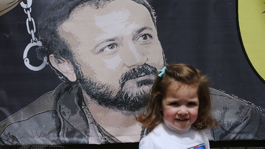Tala, the granddaughter of Fatah leader Marwan Barghuti, stands in front of a poster bearing his portrait in the West Bank city of Ramallah on April 15, 2015.