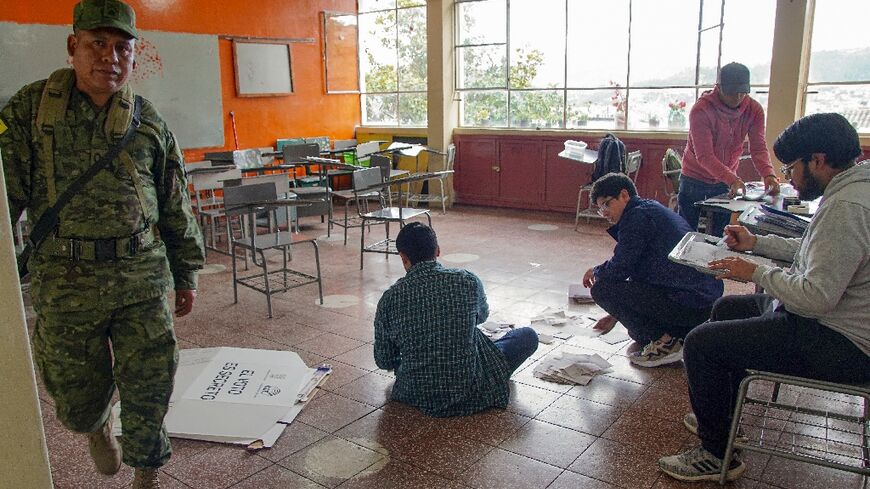 Electoral workers examine ballots while counting votes at a polling station in Cuenca, Ecuador, on October 15, 2023