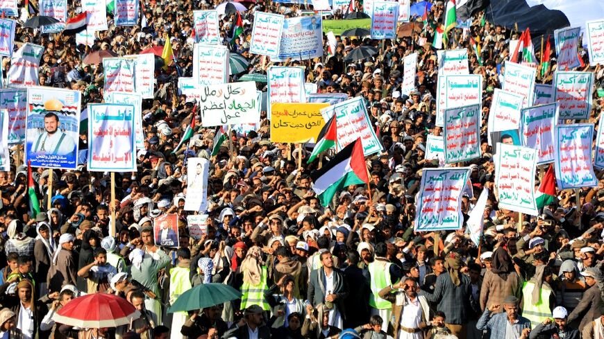 Yemenis lift placards and wave Palestinian flags as they march in the Huthi-run capital Sanaa on February 23, 2024