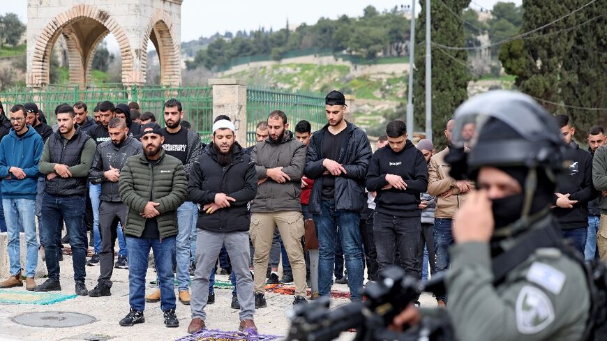 Israeli security forces stand guard as Palestinian Muslims perform Friday Noon prayers on a street in east Jerusalem on February 23, 2024