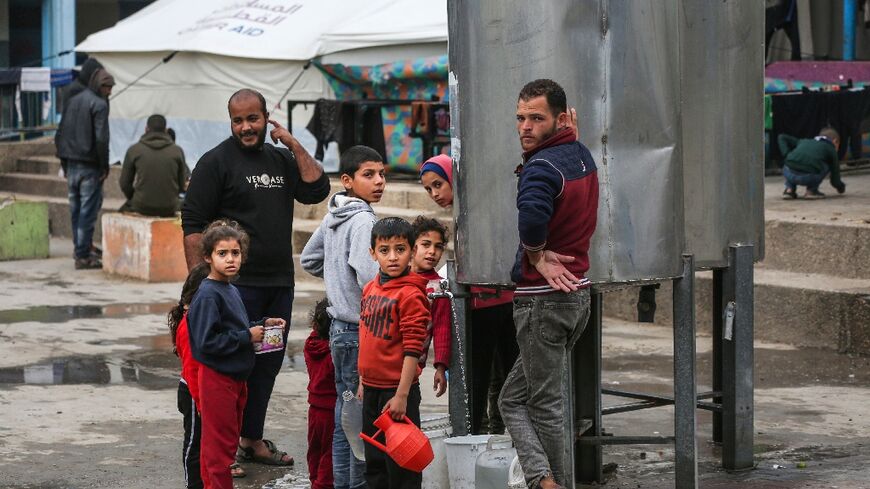 People collect water in the Maghazi camp for Palestinian refugees in the central Gaza Strip on February 27, 2024
