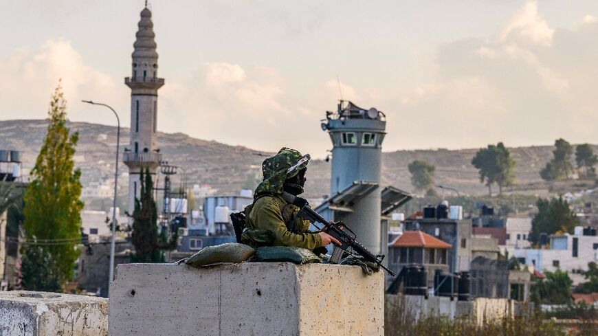 An Israeli soldier mans a checkpoint at the al-Aroub camp for Palestinian refugees south of Bethlehem in the occupied West Bank