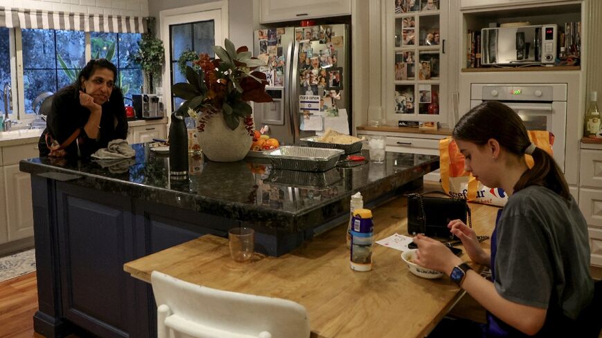 Sigal Chayak, displaced from northern Israel, looks on as her daughter Shani tastes the food she prepared in a host kitchen in Tel Aviv 