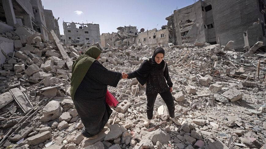 Palestinians walk in the rubble of buildings destroyed in Israel's bombardment of Khan Yunis