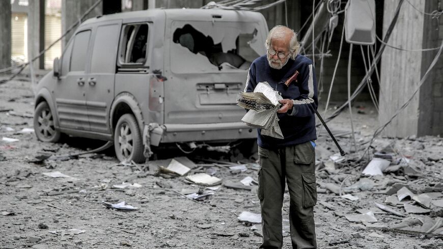 A Palestinian man reads a book in a Gaza City street damaged by Israeli bombardment 