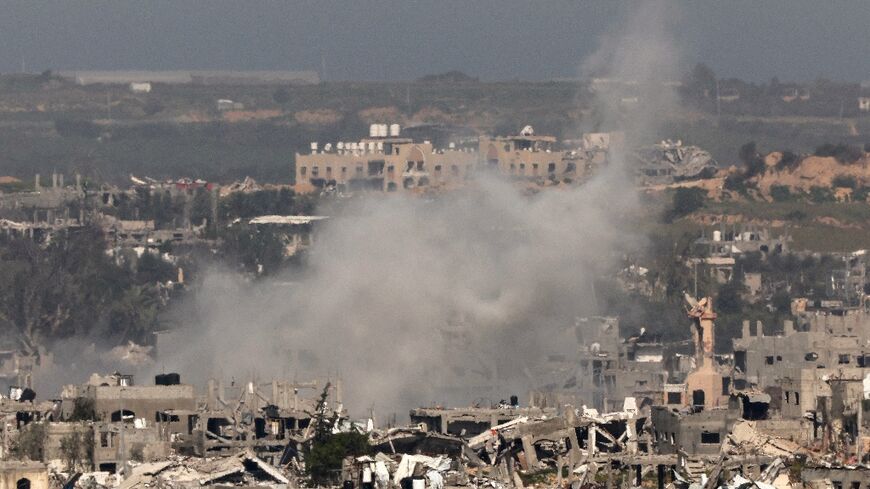A picture taken from southern Israel on March 6, 2024 shows smoke billowing amid destroyed buildings in the Gaza Strip 