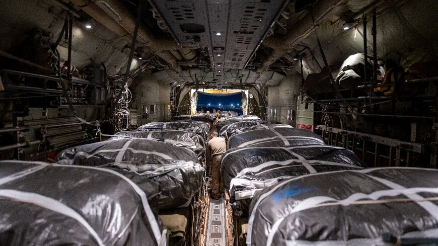 Humanitarian aid pallets rigged with parachutes for an airdrop over Gaza are loaded and prepared for takeoff onboard a US military cargo plane