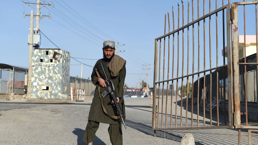 In this photo taken on February 18, 2022 a Taliban fighter stands guard at the entrance gate of Afghan-Iran border crossing bridge in Zaranj. (Photo by Wakil KOHSAR / AFP) (Photo by WAKIL KOHSAR/AFP via Getty Images)