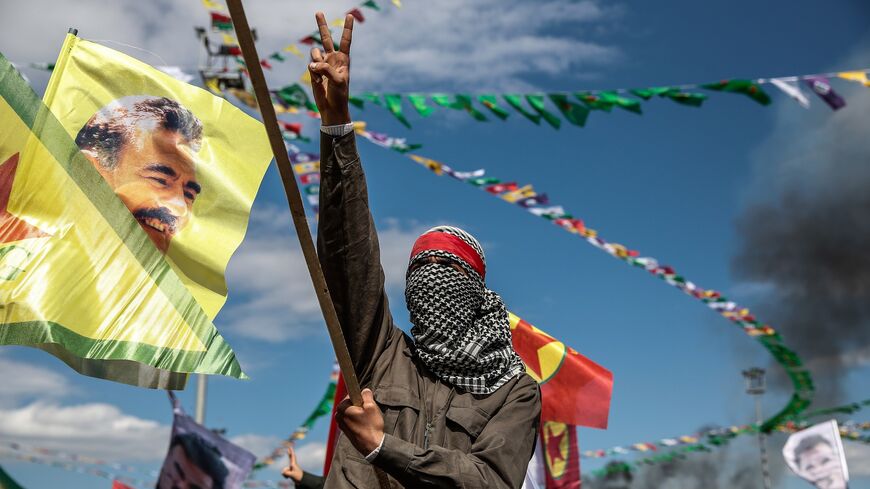 A Kurdish man wearing a mask flashes the "V" sign.