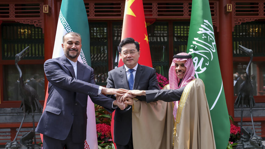 Iran's Foreign Minister Hossein Amirabdollahian, left, hold hands with his Saudi Arabian counterpart Prince Faisal bin Farhan Al Saud, right, and China's counterpart Qin Gang in Beijing Thursday, April 6, 2023 to finalize a deal that would reopen embassies, resume direct flights and restart security and trade agreements.