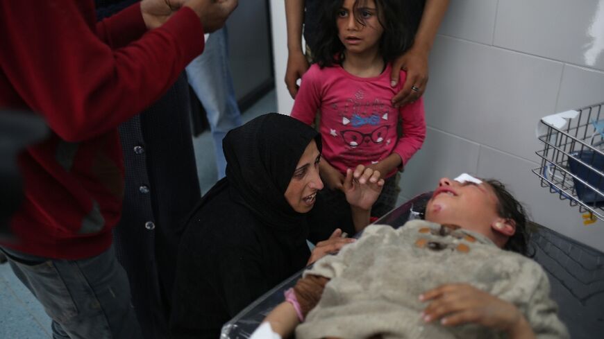 A young Palestinian girl is comforted by her family as she receives treatment after a deadly Israeli strike on a camp near a hospital in the south Gaza city of Rafah