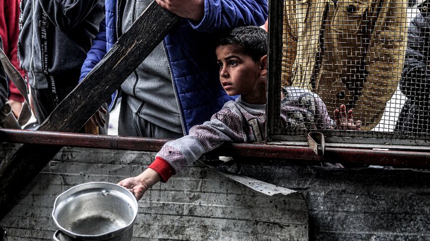 A boy holds waits for a meal provided by a charity, with food in besieged Gaza increasingly hard to find