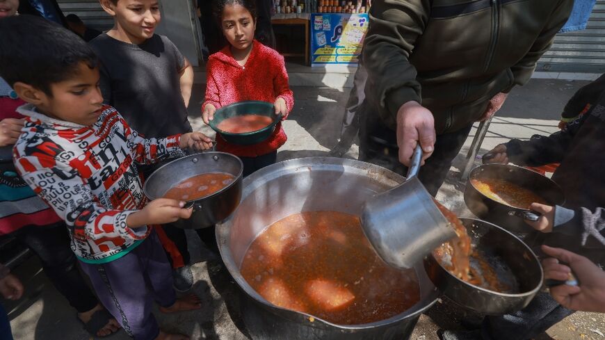 Palestinian children receive soup rations in Rafah in the southern Gaza Strip on March 5, 2024, amid widespread hunger in the besieged Palestinian territory 