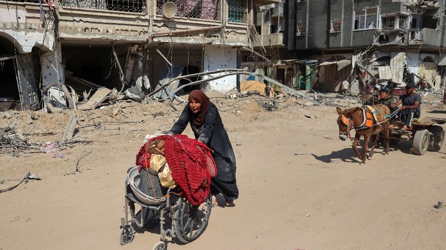 A Gazan woman pushes her belongings in a wheelchair as she returns to her home in devastated Khan Yunis Sunday after the Israeli army withdrew from the city