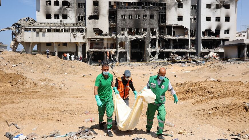 Palestinian forensic and civil defence workers recover human remains from the grounds of Al-Shifa hospital devastated by a two-week Israeli raid
