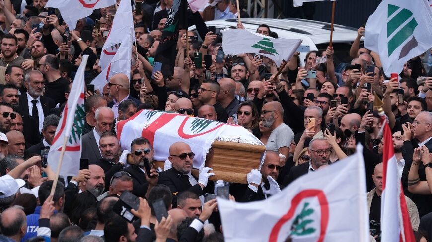 Mourners and supporters of the Lebanese Forces wave their party's flag at Sleiman's funeral