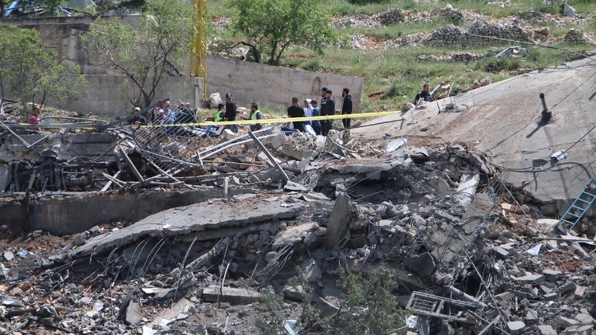 People gather around a destroyed building targeted by Israel in Lebanon's Baablbek district