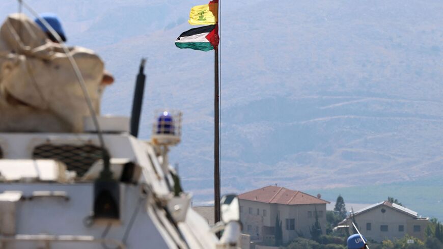 The Palestinian flag and the flag of Hezbollah wave in the wind on a pole as peacekeepers from the United Nations Interim Force in Lebanon (UNIFIL) patrol the border area between Lebanon and Israel on Hamames hill in the Khiyam area of southern Lebanon, on Oct. 13, 2023. 