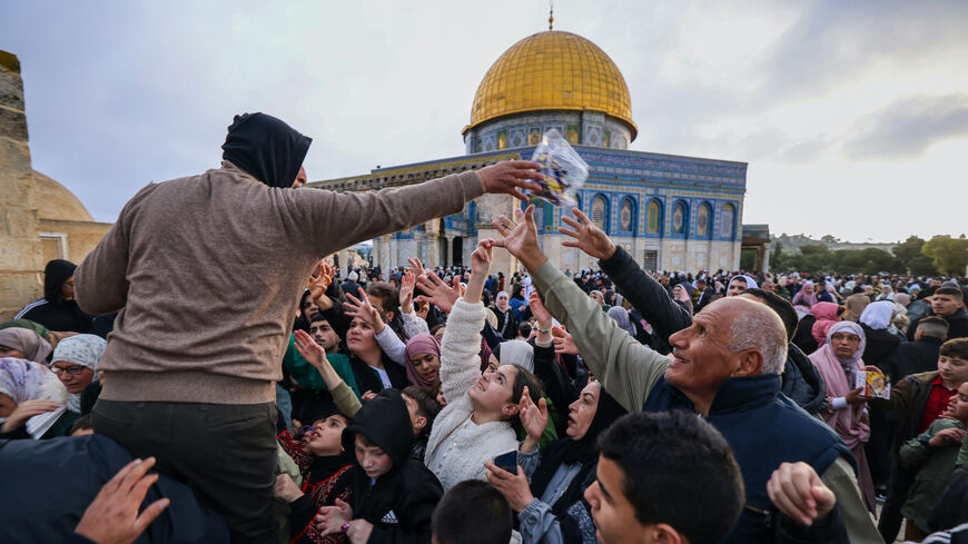 A volunteer distributes sweets to Muslims after special morning prayers to start the Eid al-Fitr festival, which marks the end of the holy fasting month of Ramadan, at the Al-Aqsa Mosque compound in Jerusalem on April 10, 2024.