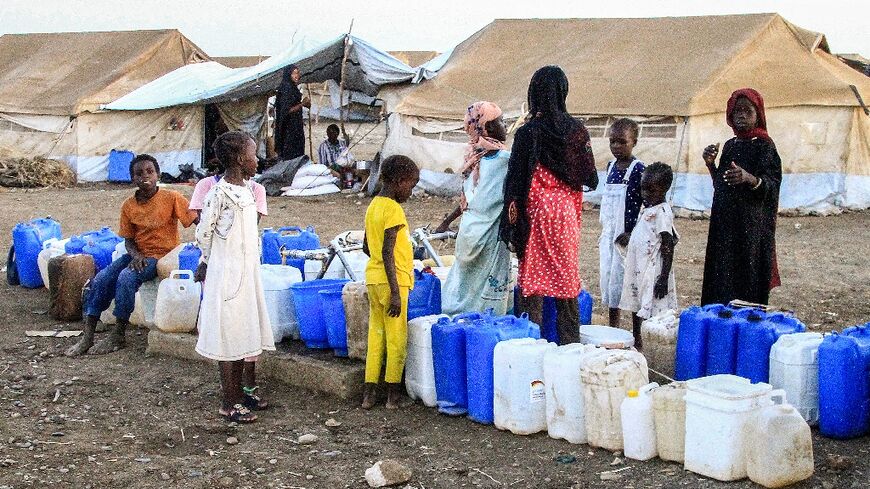 Women and children queue for water at Huri camp for the displaced south of Gedaref in east Sudan, on March 29