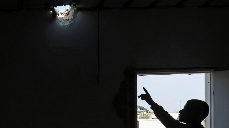 A relative points to a hole in the roof of a building caused by a projectile that injured seven-year-old Bedouin girl Amina in her village in the southern Negev desert on April 14, 2024