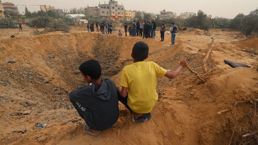 Two Palestinian boys look at a huge crater following an overnight Israeli bombardment in Rafah, southern Gaza Strip