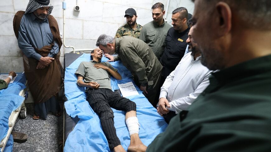 Abu Fadak Al-Mohammedawi (C-R), the chief of staff of Iraq's Popular Mobilisation Forces, visits a man at a hospital in Hilla in the central province of Babylon after he was wounded in an explosion overnight