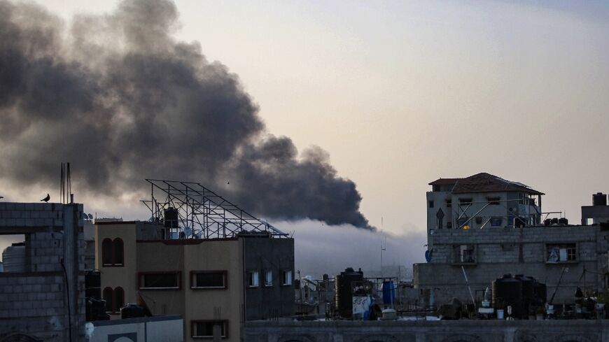 Smoke rises above buildings at sunrise in the aftermath of Israeli bombardment in Rafah in the southern Gaza Strip 