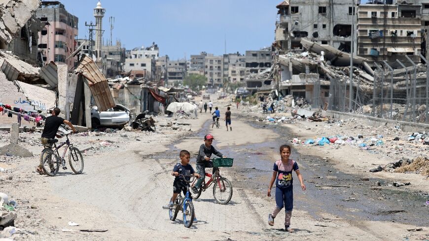 Palestinian children ride their bicycles along a street devastated by Israeli bombardment in Gaza City on May 3, 2024