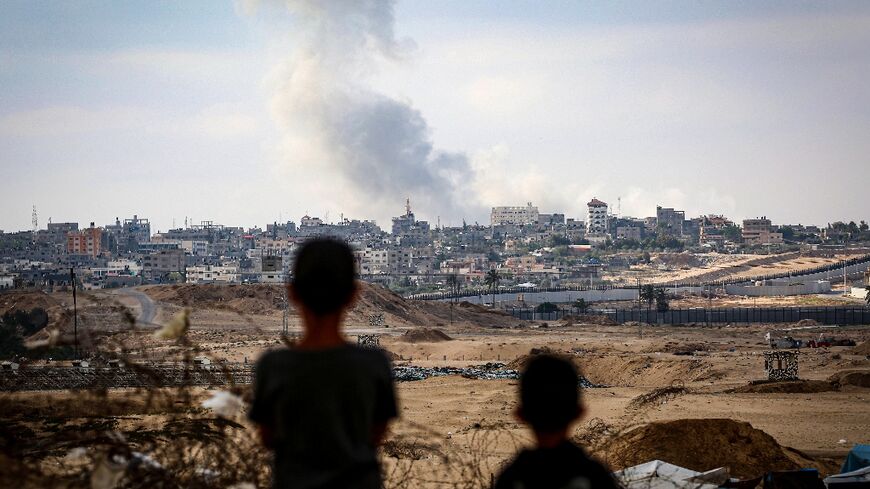 Boys watch smoke billowing during Israeli strikes east of Rafah in the southern Gaza Strip on May 13, 2024
