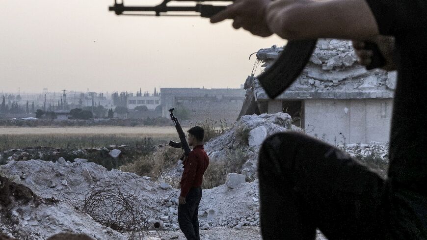 A pro-Turkish Syrian fighter holds an assault rifle at a camp for people displaced by conflict in Syria's northern Aleppo province