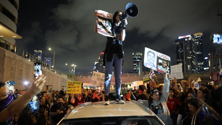 A woman holds a sign identifying Matan Zangauker (24), one of the hostages taken captive by Palestinian militants in the Gaza Strip during the Oct. 7 attacks, as she stands on the roof of a car during a demonstration by hostages' relatives and supporters in the Israeli coastal city of Tel Aviv on May 6, 2024, amid the ongoing conflict in the Gaza Strip between Israel and the Palestinian militant Hamas group. 