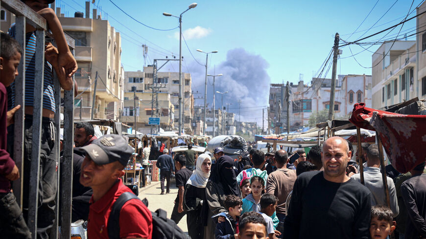 Palestinians crowd a street as smoke billows nearby from Israeli strikes in Rafah in the southern Gaza Strip on May 7, 2024, amid the ongoing conflict between Israel and the Palestinian militant group Hamas. 